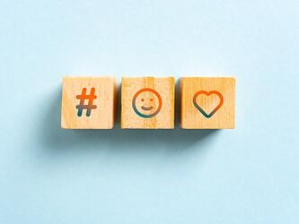 three wooden blocks showing hashtag, smiling face and loveheart